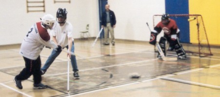 Two athletes in front of goalie, coach in background